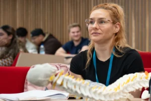 Physiotherapy student in lecture with spine prop
